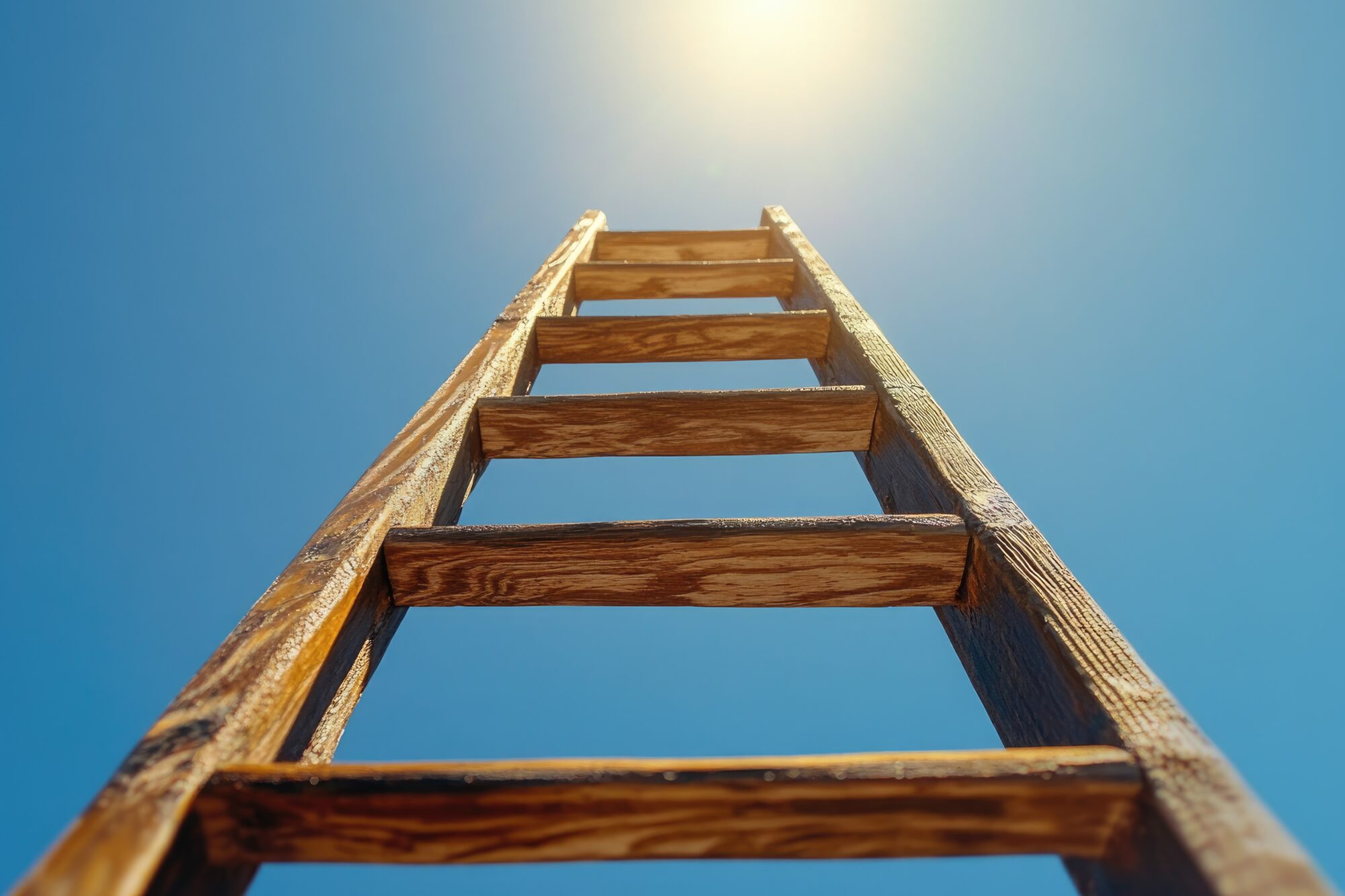 A wooden ladder reaching towards a bright blue sky, symbolizing ambition, growth, and striving for success in pursuit of the American Dream